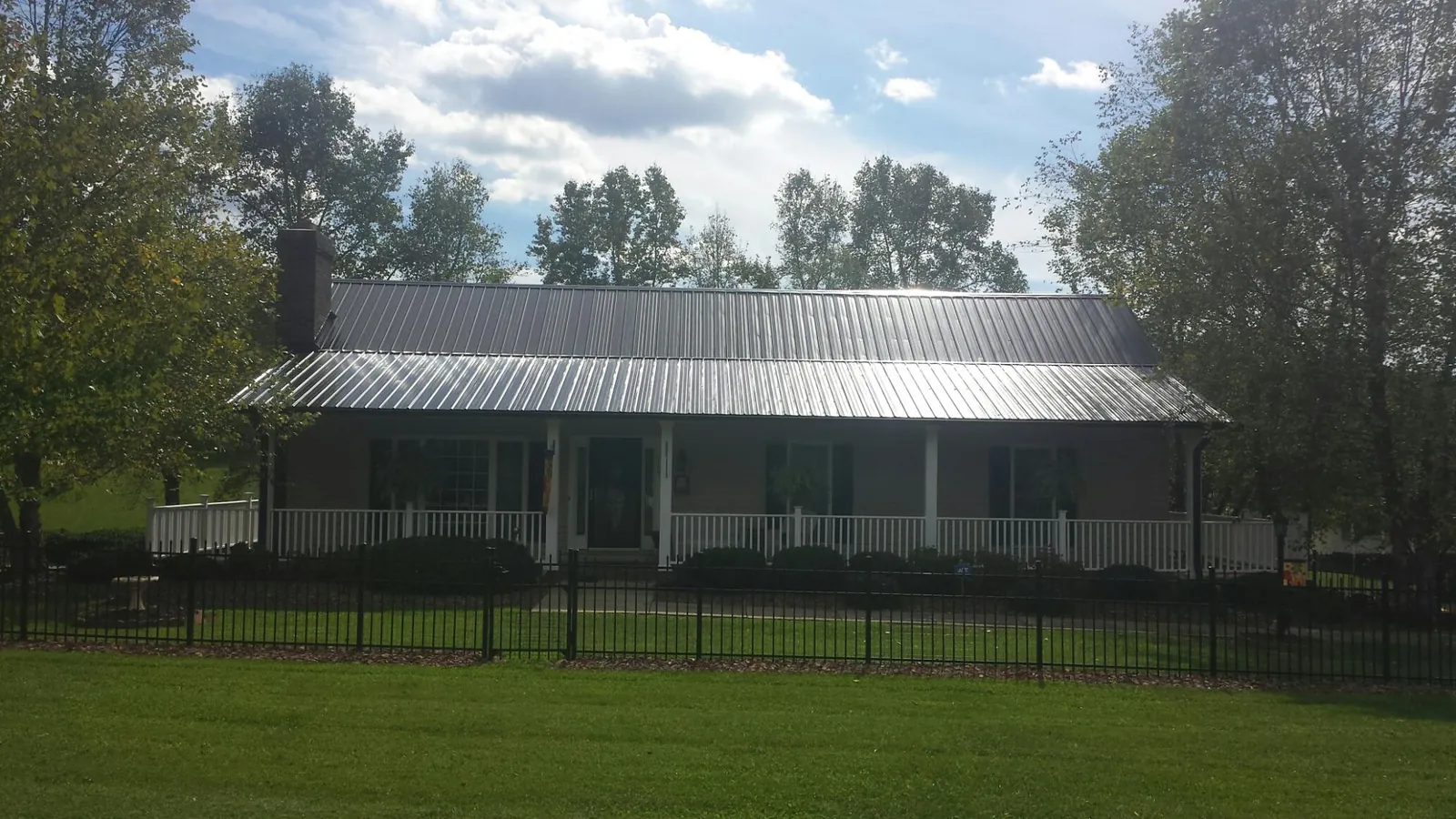Gray metal roof on a brick ranch with a full width front porch — Gutter Guard Installation work by our crew in Newell